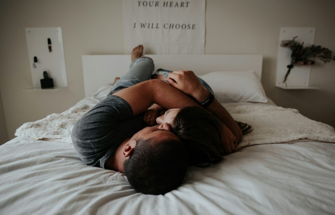 A man and woman cuddling together in bed.