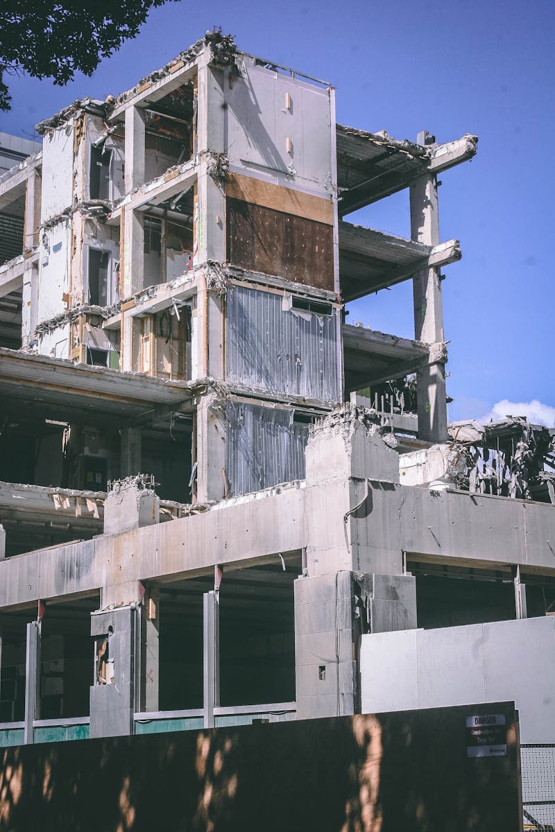 A partially demolished building in an urban setting under a clear blue sky, captured outdoors during the day.