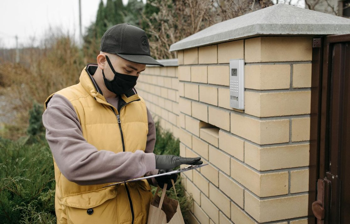 Courier wearing a mask and gloves delivering a package during COVID-19. Safety and efficiency.