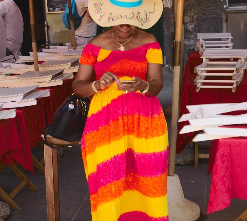 woman in yellow and red sleeveless dress wearing white sun hat
