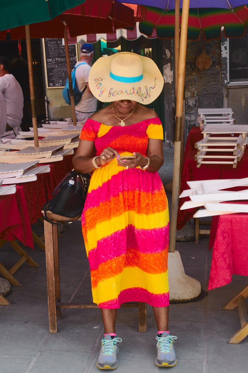 woman in yellow and red sleeveless dress wearing white sun hat