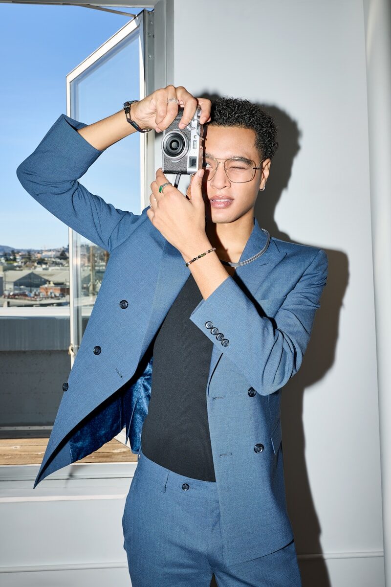 Stylish man in blue suit uses vintage camera.